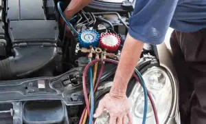 Mechanik sprawdza ciśnienie w układzie klimatyzacji, co może pomóc zdiagnozować zapchany osuszacz klimatyzacji objawy.