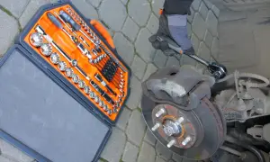 Zestaw kluczy i ręka w rękawicy próbująca wykręcić śrubę, która nie chce się wykręcić.