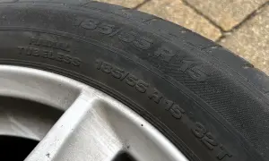 Opona samochodowa 185/55 R 15, widoczna na zewnątrz, na tle kostki brukowej.