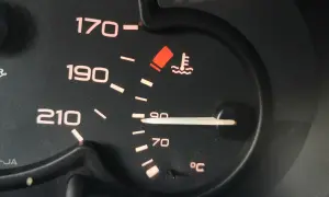 Wskaźnik temperatury silnika pokazuje 90°C. Niepokojący czerwony symbol ostrzega przed przegrzaniem, co może wpłynąć na temperaturę zapłonu oleju silnikowego.