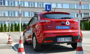 Czerwony samochód z literą "L" na dachu i napisem "EGZAMIN" na klapie bagażnika, gotowy do nauki, jak zdać to cholerne prawo jazdy.