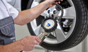 Mechanik sprawdza ciśnienie w oponie za pomocą manometru, pokazując, jak działają czujniki ciśnienia w oponach.