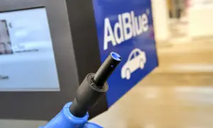 Niebieski pistolet do tankowania AdBlue na stacji paliw. Obok ekran z ceną i logo AdBlue z samochodem. Nie jest to benzyna.
