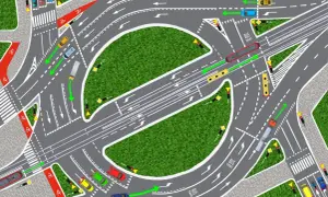 Intensywny ruch na rondzie: samochody, autobus, ciężarówka i taksówki poruszają się po wielopasmowym skrzyżowaniu z sygnalizacją świetlną i ścieżkami rowerowymi.