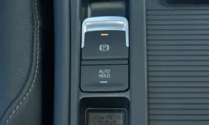 Przycisk "AUTO HOLD" w samochodzie, obok hamulca ręcznego. Ułatwia postój bez trzymania pedału hamulca.