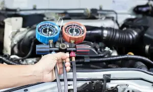Mechanik sprawdza ciśnienie w układzie klimatyzacji, by ocenić, ile trwa nabijanie klimatyzacji.