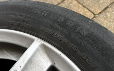 Opona samochodowa 185/55 R 15, widoczna na zewnątrz, na tle kostki brukowej.