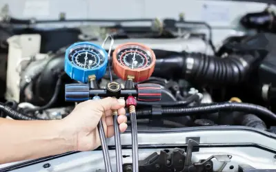 Mechanik sprawdza ciśnienie w układzie klimatyzacji, by ocenić, ile trwa nabijanie klimatyzacji.