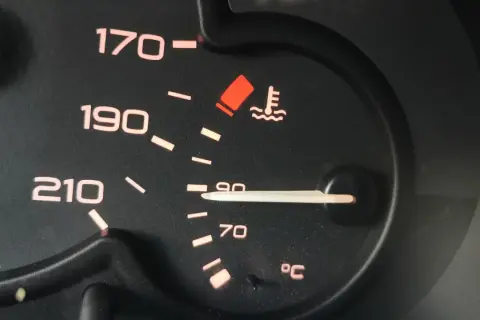 Wskaźnik temperatury silnika pokazuje 90°C. Niepokojący czerwony symbol ostrzega przed przegrzaniem, co może wpłynąć na temperaturę zapłonu oleju silnikowego.