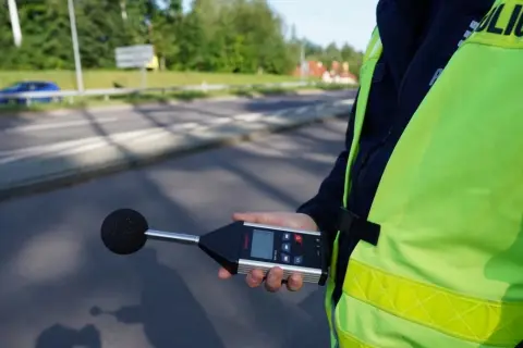 Policjant mierzy poziom hałasu emitowanego przez auto. Sprawdza, ile dB może mieć auto, by nie przekraczać norm.