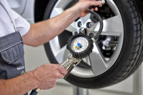 Mechanik sprawdza ciśnienie w oponie za pomocą manometru, pokazując, jak działają czujniki ciśnienia w oponach.
