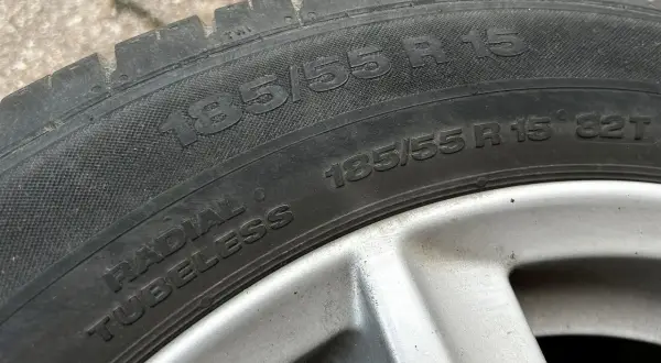 Opona samochodowa z napisem 185/55 R 15. Jest to opona typu radial tubeless, gotowa do montażu.