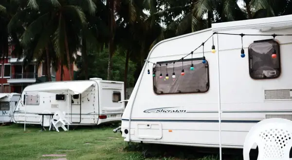 Kemping pod palmami, przyczepy kempingowe z girlandami światełek. Zastanawiasz się, jakie prawo jazdy na przyczepę kempingową?