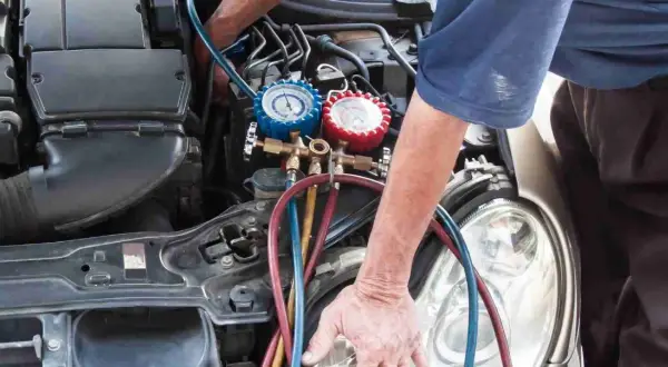 Mechanik sprawdza ciśnienie w układzie klimatyzacji, co może pomóc zdiagnozować zapchany osuszacz klimatyzacji objawy.