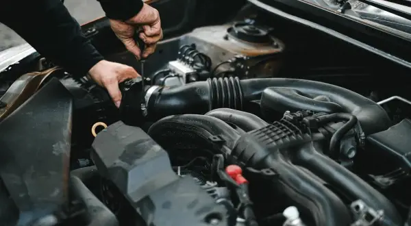 Mechanik dokręca śrubę przy silniku. Może to być związane z uszkodzonym przekaźnikiem pompy paliwa objawy, które utrudniają rozruch auta.