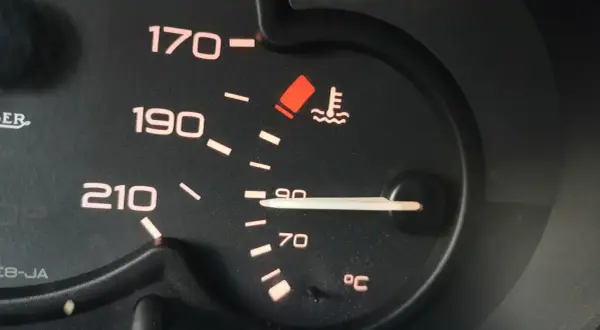 Wskaźnik temperatury silnika pokazuje 90°C. Niepokojący czerwony symbol ostrzega przed przegrzaniem, co może wpłynąć na temperaturę zapłonu oleju silnikowego.