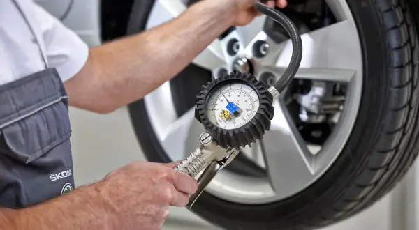 Mechanik sprawdza ciśnienie w oponie za pomocą manometru, pokazując, jak działają czujniki ciśnienia w oponach.