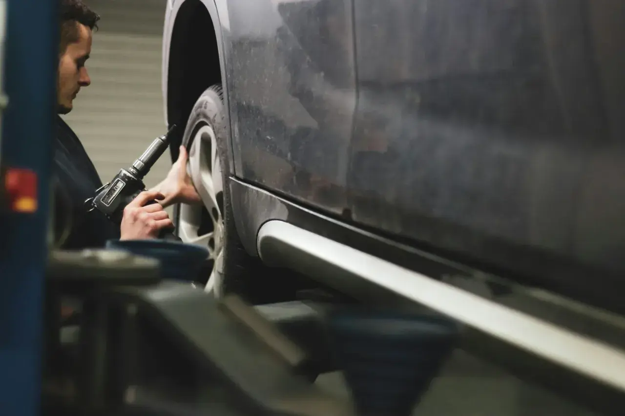 Mechanik dokręca śruby koła kluczem pneumatycznym, dbając o prawidłową zbieżność dodatnią.