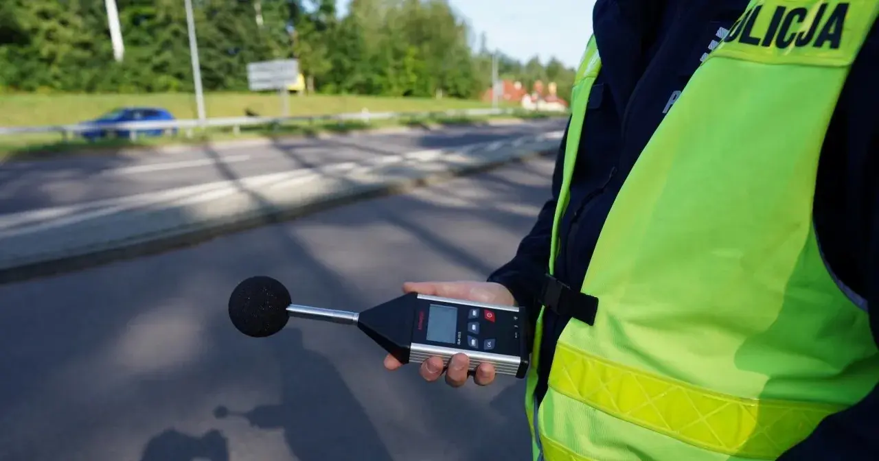 Policjant mierzy poziom hałasu emitowanego przez auto. Sprawdza, ile dB może mieć auto, by nie przekraczać norm.