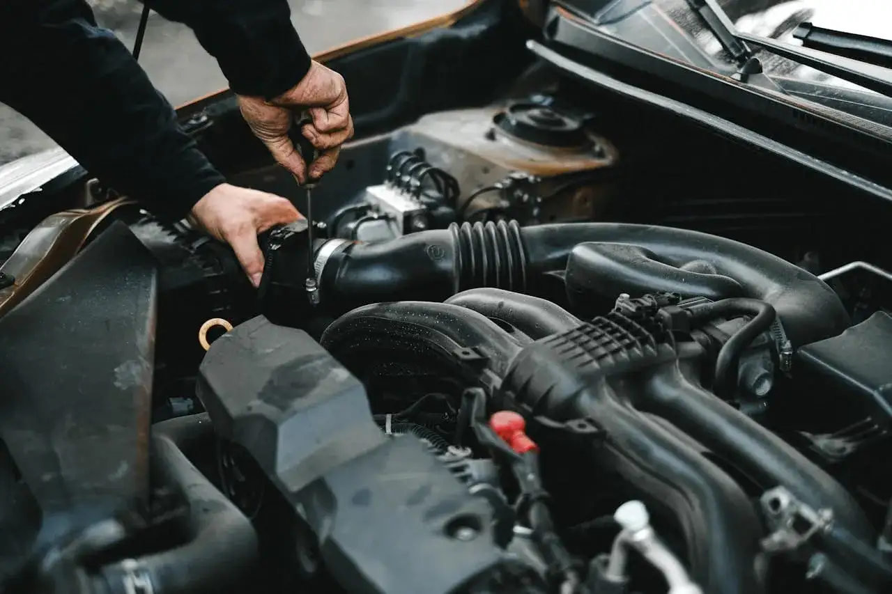 Mechanik dokręca śrubę przy silniku. Może to być związane z uszkodzonym przekaźnikiem pompy paliwa objawy, które utrudniają pracę auta.