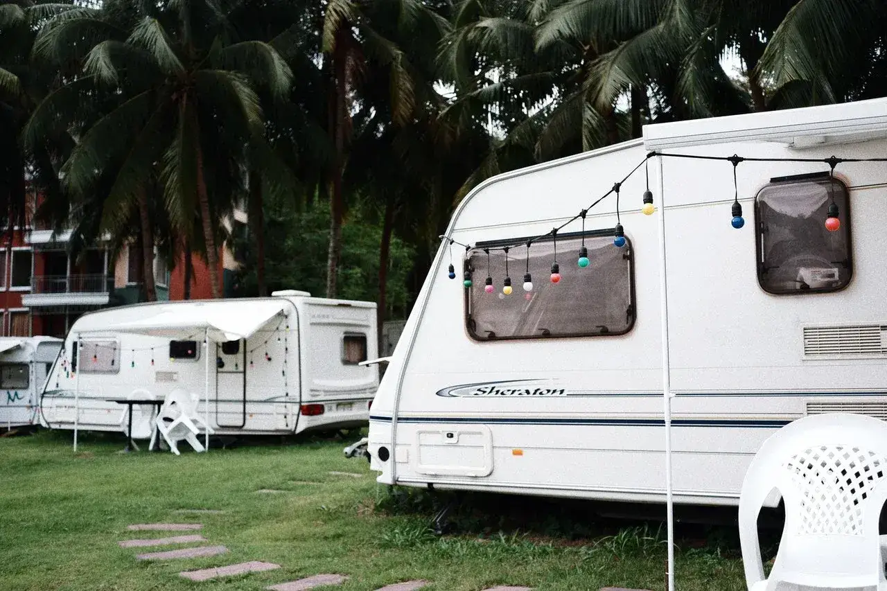 Kemping pod palmami, przyczepy kempingowe z girlandami świateł. Zastanawiasz się, jakie prawo jazdy na przyczepę kempingową?