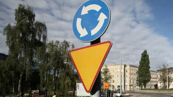 Rondo bez znaku ustąp pierwszeństwa. Znak informuje o ruchu okrężnym, a obok niego znajduje się żółty trójkątny znak ostrzegawczy.