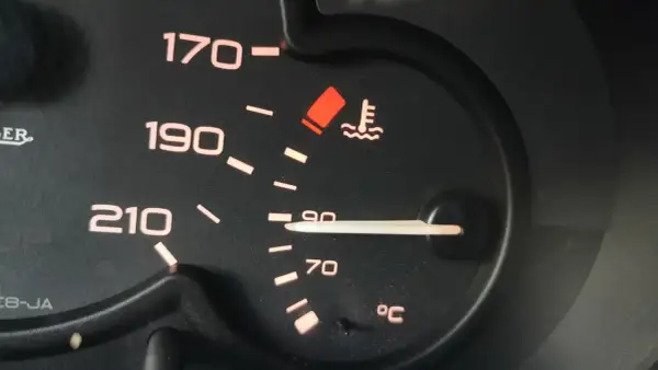 Wskaźnik temperatury silnika pokazuje 90°C. Niepokojący czerwony symbol ostrzega przed przegrzaniem, co może wpłynąć na temperaturę zapłonu oleju silnikowego.