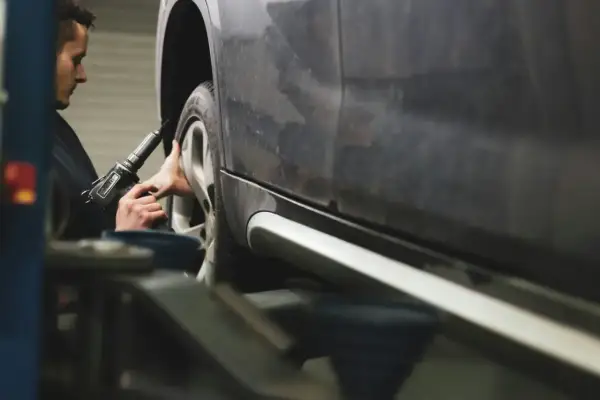 Mechanik dokręca śruby koła kluczem pneumatycznym, dbając o prawidłową zbieżność dodatnią.
